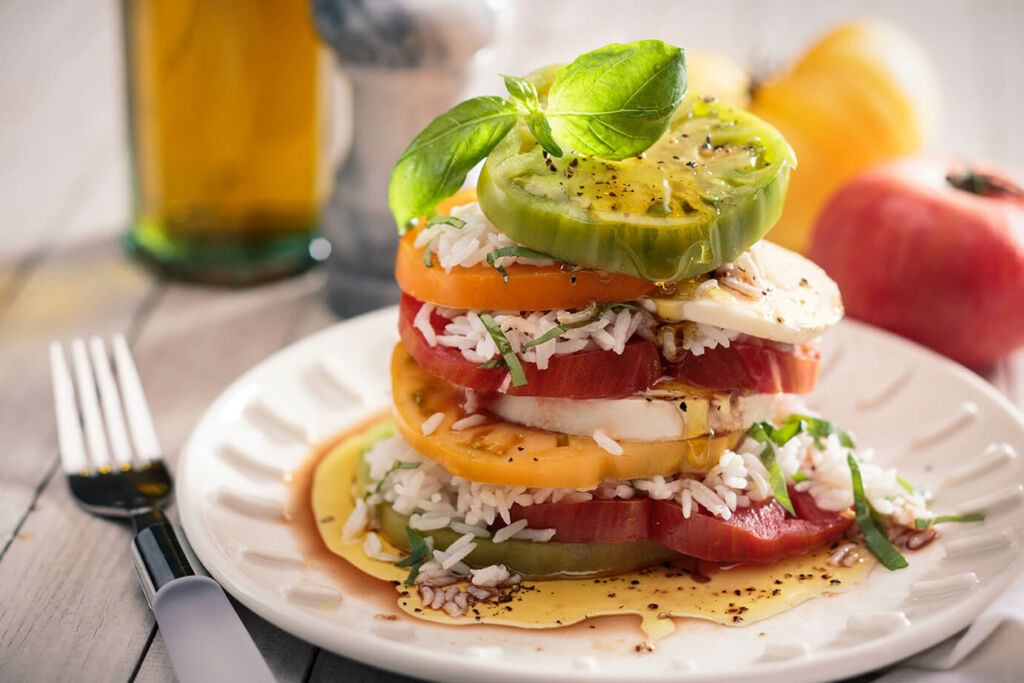 Layered caprese salad with white rice, basil and mozzarella 